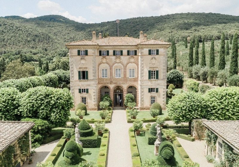 A stone villa in Tuscany with formal gardens, topiary and cypress trees in front